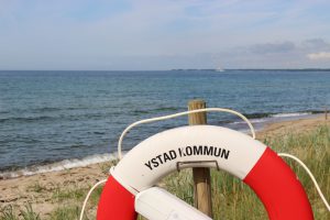 Lifebelt in front of the Baltic sea. The label on the lifebelt says: Kommune of Ystad. Ystad is film location of the crime series Wallander.