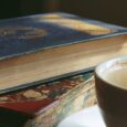 Två äldre böcker med rikt dekorerade pärmar bredvid en kopp kaffe